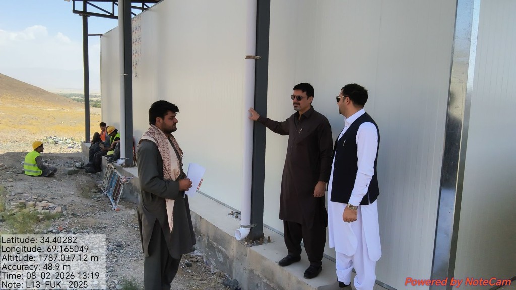 Monitoring team reviewing a prefabricated building on a UNHCR infrastructure site in Afghanistan